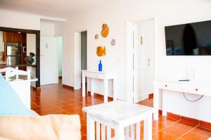 a living room with white tables and a tv at Famara Surf in Famara