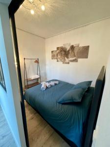 een slaapkamer met een groot bed met blauwe lakens en kussens bij Escale Confort in Montlhéry