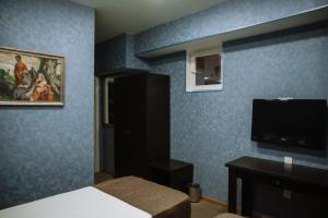 Address Boutique Hotel Baku في باكو: غرفة نوم بجدران زرقاء مع سرير وتلفزيون بشاشة مسطحة