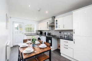 cocina con armarios blancos y mesa de madera en Delightful House with Garden, en Sherburn in Elmet