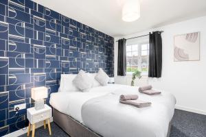 a bedroom with two beds and a blue accent wall at Delightful House with Garden in Sherburn in Elmet