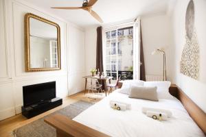 a white bedroom with a large white bed and a mirror at GuestReady - Charming Studio 10 mins to Louvre in Paris