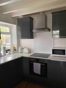 a kitchen with black cabinets and a stove top oven at Contemporary Duplex: Private Patio, Secure Parking in Stockport