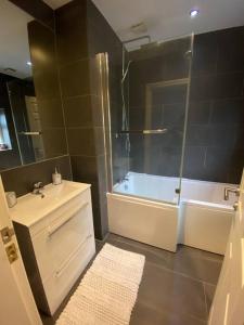 a bathroom with a tub and a sink and a shower at Contemporary Duplex: Private Patio, Secure Parking in Stockport