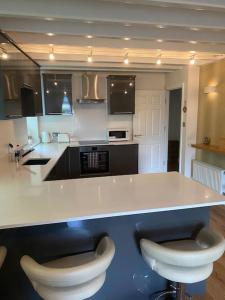a kitchen with a white counter and two stools at Contemporary Duplex: Private Patio, Secure Parking in Stockport