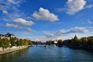 a river with a boat on it in a city at GuestReady - Charming Studio 10 mins to Louvre in Paris