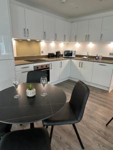 a kitchen with a table and two chairs and a kitchen with white cabinets at Immaculate 2-Bed Apartment in Canning Town in London