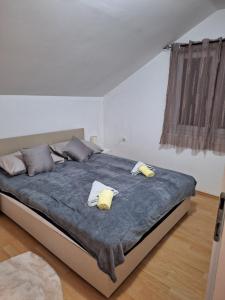 a bedroom with a large bed with two yellow pillows at APARTMAN ŽELJA in Sremska Mitrovica