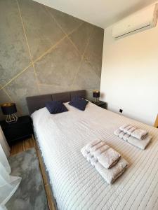 a bedroom with a white bed with towels on it at Stylowy Apartament w Serocku in Serock