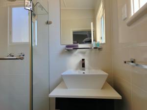 La salle de bains est pourvue d'un lavabo blanc et d'une douche. dans l'établissement Altair Motel, à Cooma
