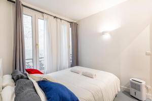 a white bedroom with a bed and a window at GuestReady - Patriotic Blank Canvas near Louvre in Paris