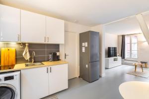 a kitchen with white cabinets and a stainless steel refrigerator at GuestReady - Patriotic Blank Canvas near Louvre in Paris