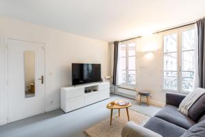 a living room with a couch and a tv at GuestReady - Patriotic Blank Canvas near Louvre in Paris