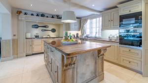 a large kitchen with a large wooden island in the middle at The Parsonage in Ombersley