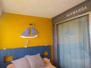 a bedroom with a blue bed and a yellow wall at ALAMANDA STUDIO LE GRAU DU ROI - in Le Grau-du-Roi