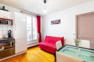 a living room with a red couch and a table at GuestReady - Memorable stay in the suburbs in Issy-les-Moulineaux