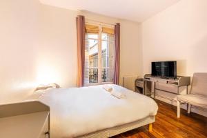 a bedroom with a bed and a tv and a window at GuestReady - Cozy Apt Near Square Louise Michel in Paris