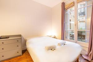 a bedroom with a bed and a window at GuestReady - Cozy Apt Near Square Louise Michel in Paris