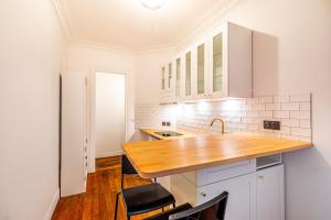 a kitchen with white cabinets and a wooden counter top at GuestReady - Cozy Apt Near Square Louise Michel in Paris