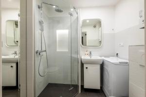 baño blanco con ducha y lavamanos en 28 Gdynia Centrum - Apartament Mieszkanie dla 2 os, en Gdynia