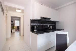 a kitchen with white cabinets and black counter tops at 28 Gdynia Centrum - Apartament Mieszkanie dla 2 os in Gdynia
