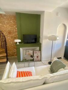 un salon avec un canapé blanc et une télévision dans l'établissement Le 23, cocon dans le centre historique, à Montauban