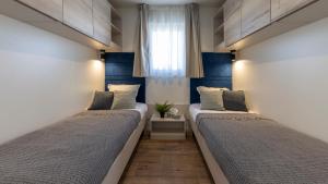 2 łóżka w pokoju z niebieskimi ścianami i oknem w obiekcie Mobile Homes Lopari w mieście Nerezine