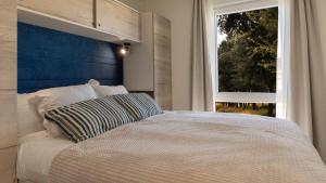 a bedroom with a bed with a blue headboard and a window at Mobile Homes Lopari in Nerezine