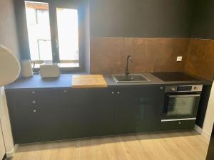 - une cuisine avec un plan de travail noir et un évier dans l'établissement Le 23, cocon dans le centre historique, à Montauban