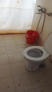 a bathroom with a toilet and a red bucket at REBO NUBRA CAMP in Hundar