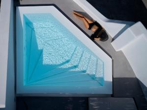 a man is standing next to a swimming pool at Phos The Boutique in Akrotiri +37 photos