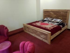 a bedroom with a bed and two pink chairs at Hill Heaven Resort in Abbottabad