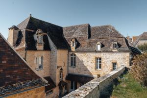 een oud stenen gebouw met ramen en een muur bij Hôtel l'Abbaye in Saint-Cyprien