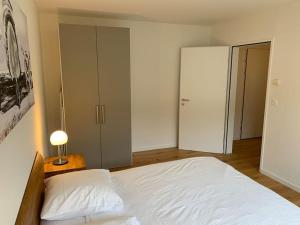 um quarto com uma grande cama branca e um candeeiro em Modern one bedroom flat close to the city - Bass1 em Bassersdorf
