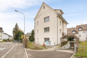 une maison blanche sur le côté d'une rue dans l'établissement Modern one bedroom flat close to the city - Bass1, à Bassersdorf