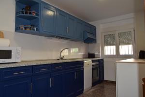 eine Küche mit blauen Schränken und einer weißen Mikrowelle in der Unterkunft Casa Rural O Noso Lar in Raspay