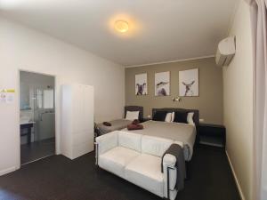 - une chambre avec un lit blanc et un canapé blanc dans l'établissement Altair Motel, à Cooma