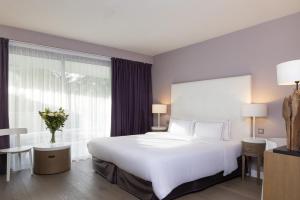 a bedroom with a white bed and a large window at Hôtel Château des Tourelles - Relais Thalasso & Spa in Pornichet +71 photos