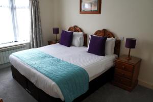 1 dormitorio con 1 cama grande con almohadas moradas en The Uplands Apartments, en Saint Helier Jersey