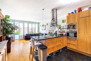 a kitchen with wooden cabinets and a living room at GuestReady - Comfort near Parc Clichy-Batignolles in Paris