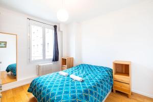 a bedroom with a blue bed and a window at GuestReady - Comfort near Parc Clichy-Batignolles in Paris
