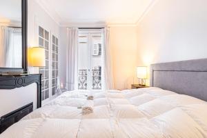 - une chambre blanche avec 2 lits et une fenêtre dans l'établissement GuestReady - Bright stay near Jardin du Luxembourg, à Paris