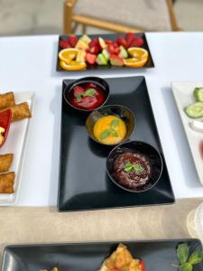 una mesa cubierta con tres platos de comida con fruta en Kronos Hotel, en Durrës