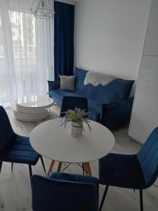 salon z niebieską kanapą, stołem i krzesłami w obiekcie Apartament MajaHouse w Nowej Soli