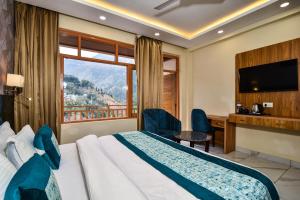 a hotel room with a bed and a desk and a window at Hotel Pawan Regency Mcleodganj in McLeod Ganj