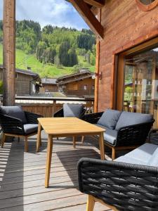 a wooden deck with a wooden table and chairs at MORZINE GUEST CHALET HYPERCENTER Jacuzzi et Sauna in Morzine