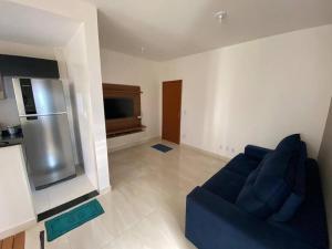a living room with a blue couch and a refrigerator at Lindo Apto Grande e Novíssimo no Centro in Juiz de Fora +2 photos