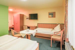 a room with two beds and a table and a tv at Hotel Ideal in Lübeck