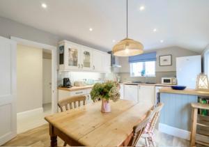 a kitchen with a wooden table with chairs and a vase of flowers at Penrose in Downderry