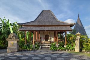 een tempel in een tuin met een gebouw bij The Alena a Pramana Experience in Ubud